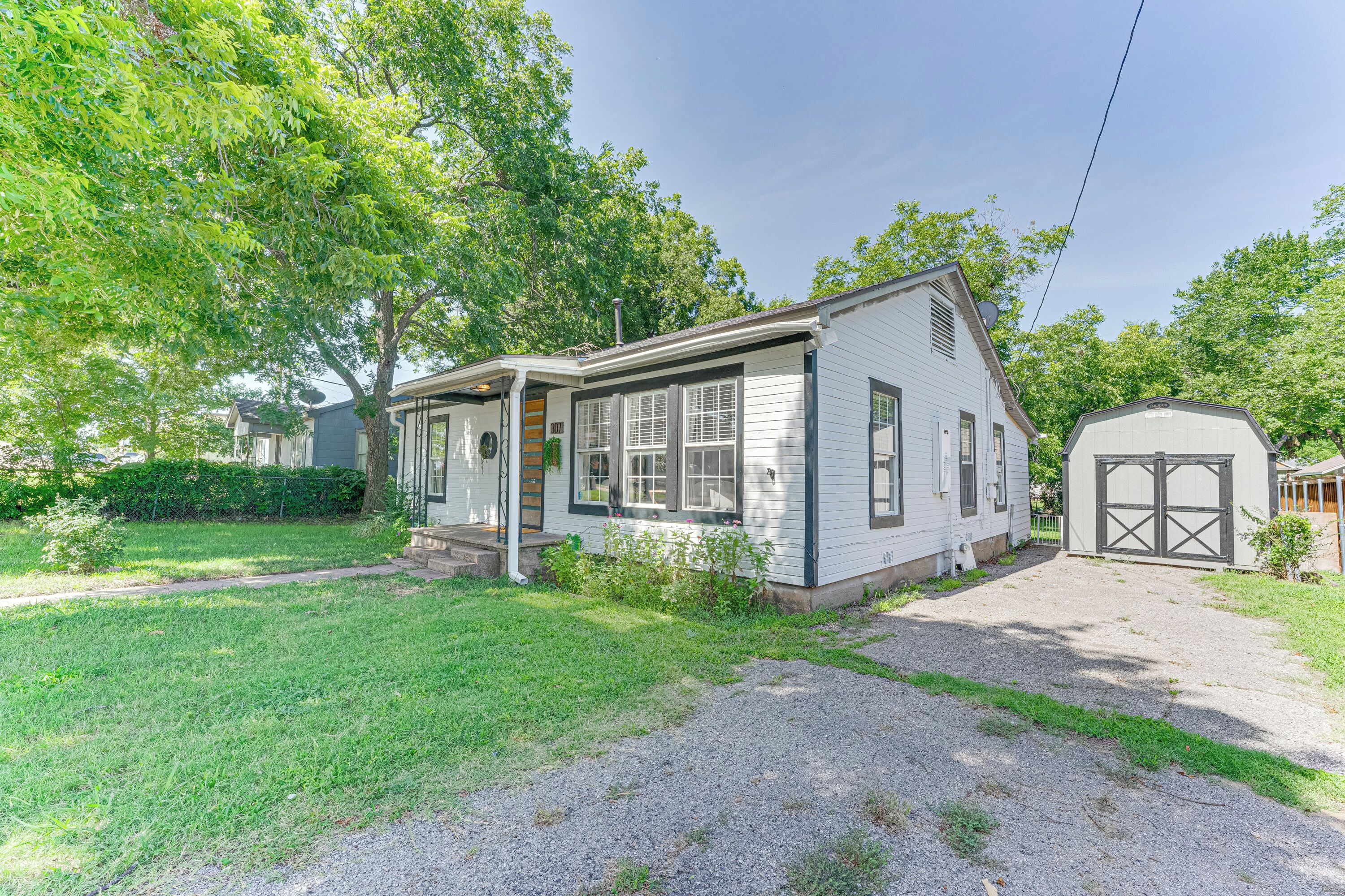 Ein eingeschossiges Haus mit Veranda, Garage und gepflegtem Rasen.