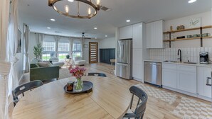 A modern kitchen with white cabinets, stainless steel appliances, and a dining area with a wooden table and chairs. - Bright Ivory Studio Getaway- Walk Shops & Dining (Midlothian)