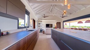 Een moderne keuken met een groot kookeiland, houten kastjes en hanglampen.