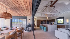 Een moderne keuken met een centraal eiland, een houten plafond en een eethoek met een tafel en stoelen.
