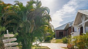 Un resort tropical con un sendero pavimentado que conduce a un edificio de madera con techo metálico.