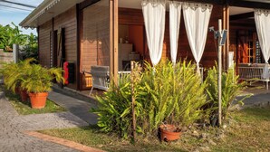 Una casa de madera con porche cubierto, un pequeño jardín y un panel solar.