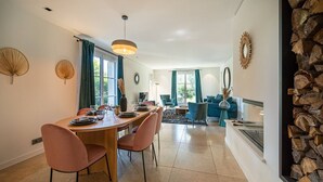 Un espace de salle à manger moderne avec une table en bois, des chaises roses et un lustre.