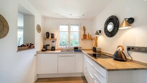Une cuisine moderne avec des meubles blancs, un plan de travail en granit, une bouilloire, un grille-pain et une machine à café.