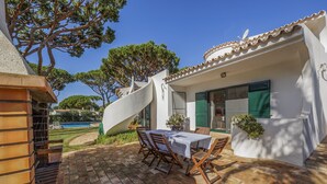 Eine Terrasse mit Tisch und Stühlen, eine Wendeltreppe und ein Pool im Hintergrund.