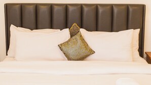 A neatly made bed with white linens, a patterned pillow, and a framed artwork above it. - Premium Three Bedroom Apartment at Clifton Place (Accra)