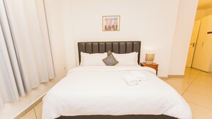 A neatly made bed with white linens, a dark headboard, and a single pillow. - Premium Three Bedroom Apartment at Clifton Place (Accra)