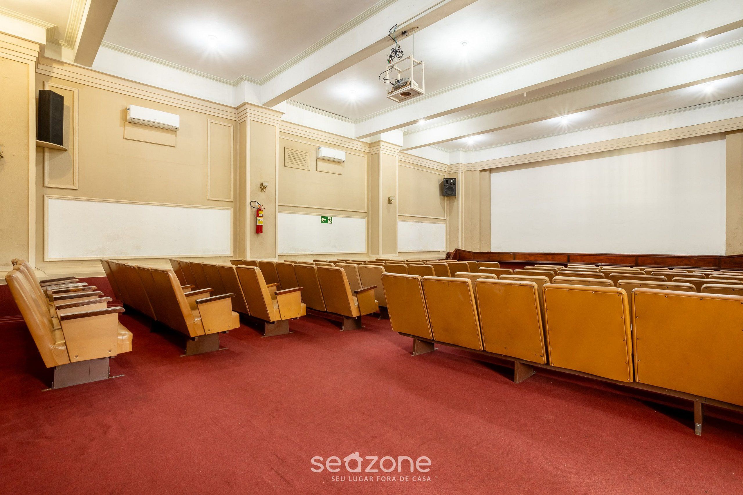 A conference room with rows of chairs, a projector, and a white screen.