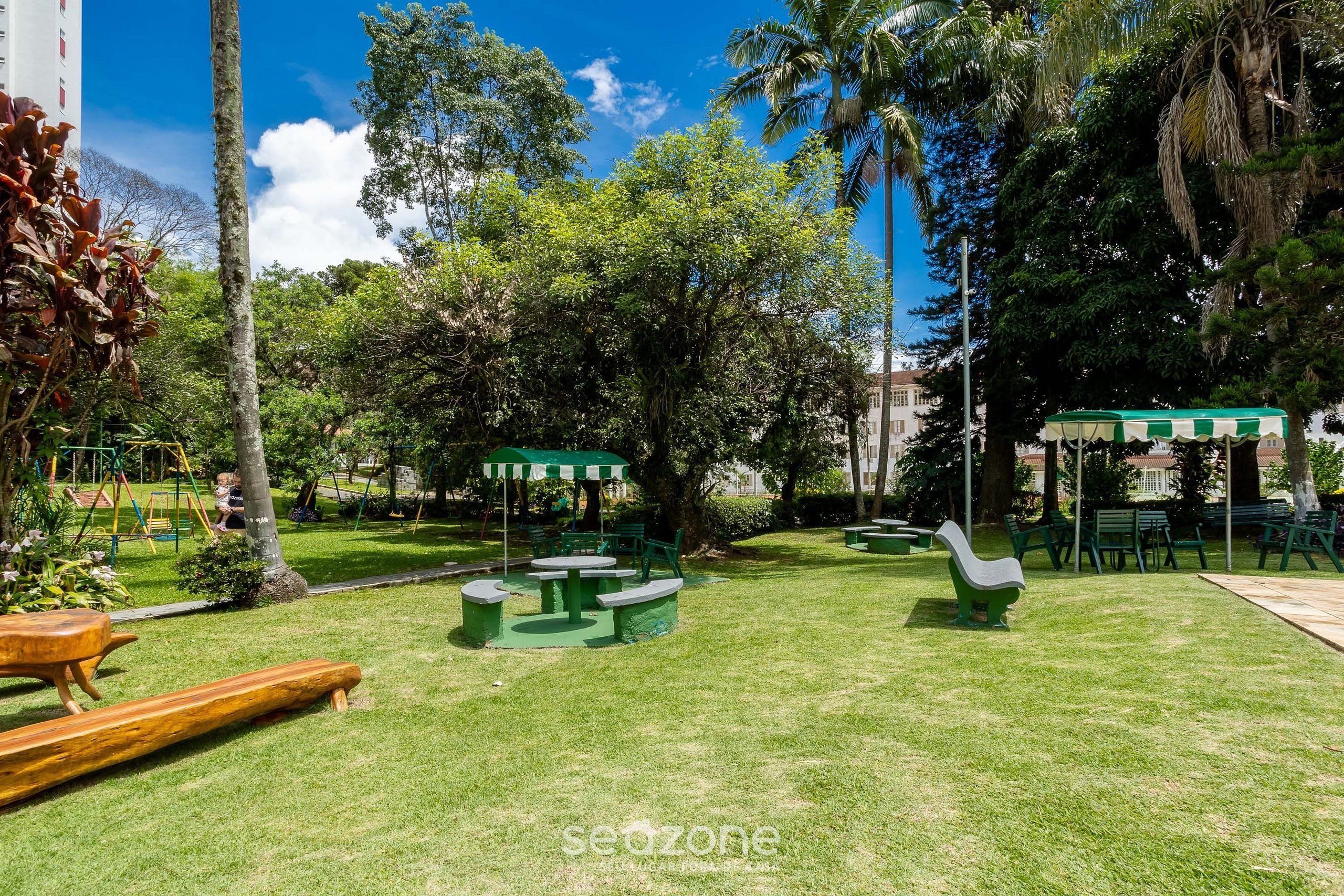 Un parque con mesas de picnic, bancos y un área de juegos.
