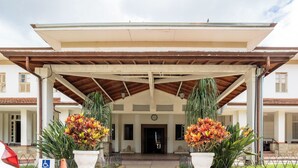 Entrada coberta com um relógio, plantas em vasos e sinal de acessibilidade para cadeiras de rodas.
