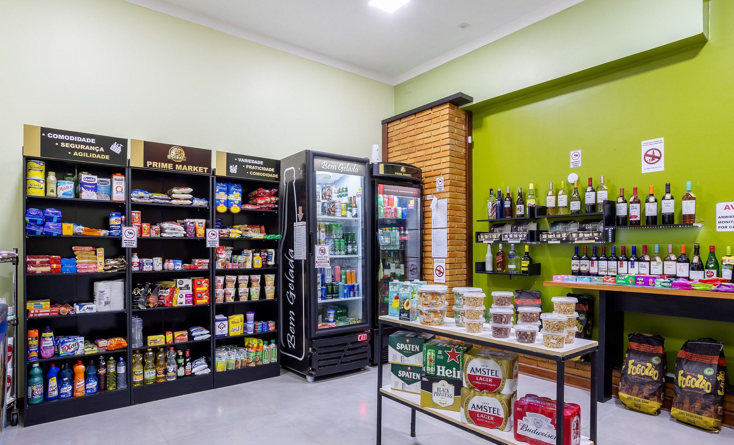 Un supermercado con estantes llenos de productos varios, una vitrina refrigerada y una sección con bebidas embotelladas.