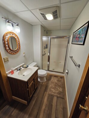 Ein Badezimmer mit Waschtisch, Waschbecken, Toilette und einer Duschkabine aus Glas.