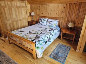 Ein Schlafzimmer mit Holzwänden, einem Bett, zwei Nachttischen und einem Teppich.
