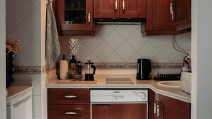 Una cucina compatta con mobili in legno, lavastoviglie e rivestimento a mosaico.