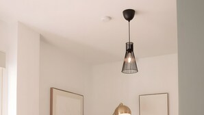Un soggiorno moderno con un divano, una lampada da terra, un tavolino con una pianta e quadri appesi al muro.