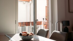 Zona pranzo con tavolo, sedie, una ciotola di pane e una lampada a sospensione particolare.