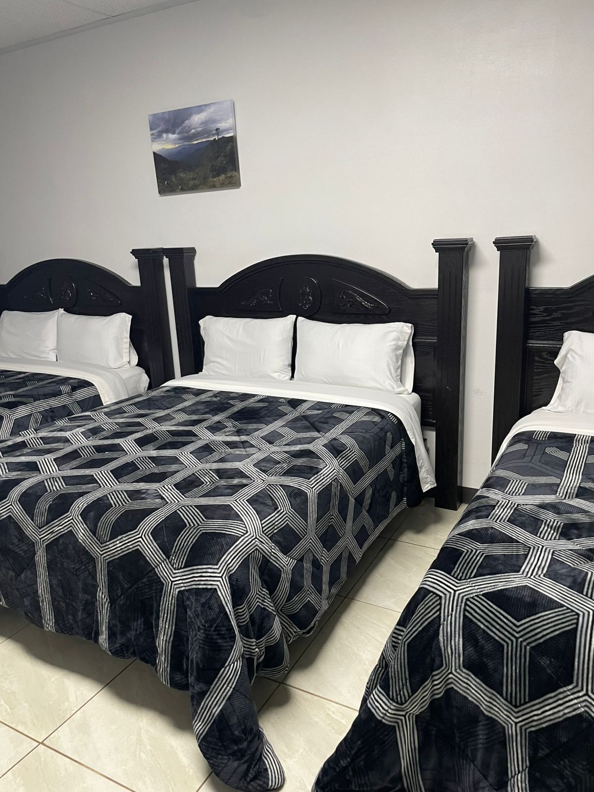 A hotel room with two beds, each with a dark headboard and white bedding.