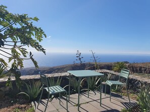 Une terrasse avec une table et des chaises donnant sur un paysage côtier.