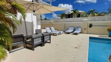 A poolside area with lounge chairs, a small table, and a pool.