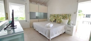 A bedroom with a bed, a desk, a chair, a wardrobe, and a window with blinds. - 3BR Caribbean Home in Porters | Walk to Beach & Pool (Porters, Saint James)