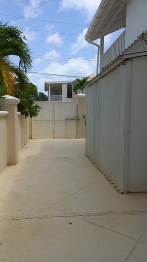 Un chemin bordé de grilles menant à un bâtiment doté d’un balcon.