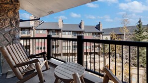 Een balkon met houten stoelen en een tafel, met uitzicht op een woongebied met huizen en bomen.