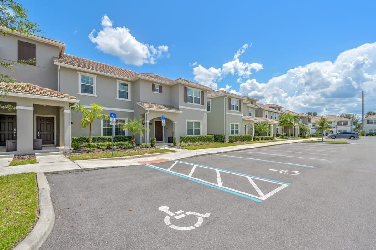 A row of townhouses with a parking lot, including a handicapped parking space.