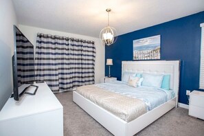 A bedroom with a bed, a desk, a chair, a lamp, and a painting on the wall. - Home 6BR - Prime Location (Kissimmee)