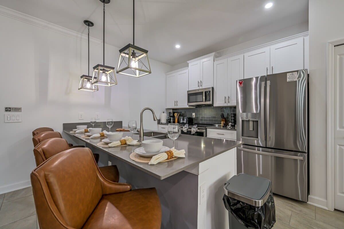 A modern kitchen with white cabinets, stainless steel appliances, and a central island with seating.