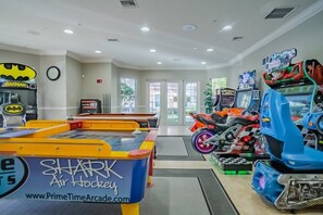 An indoor arcade with various gaming machines, including air hockey tables and racing simulators. - Prime Location-spacious Condo for 8 Guests (Orlando)