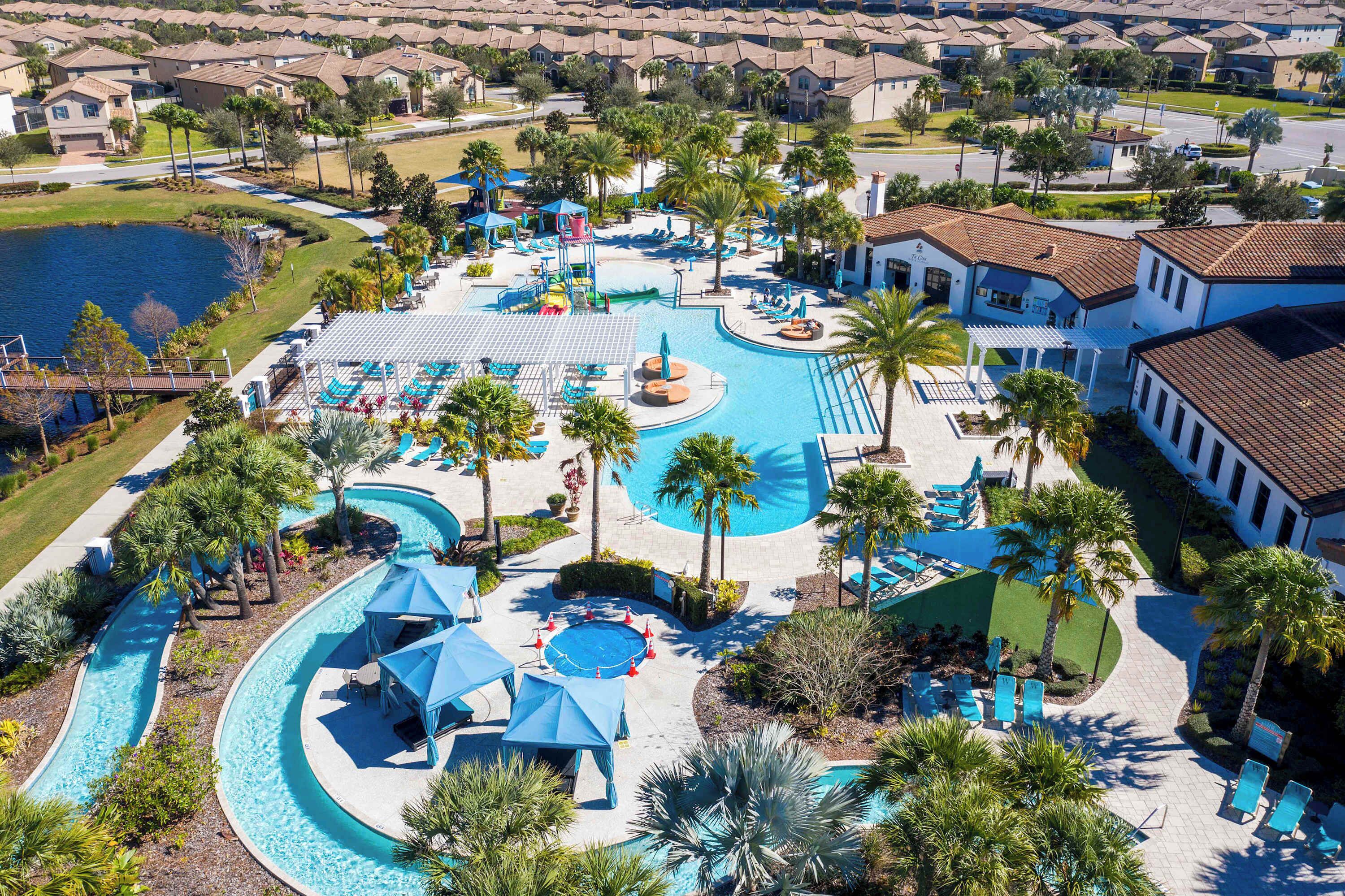 A resort with a large pool, palm trees, and a water slide.