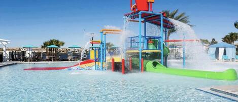 A water park with a pool, slides, and a water play structure.