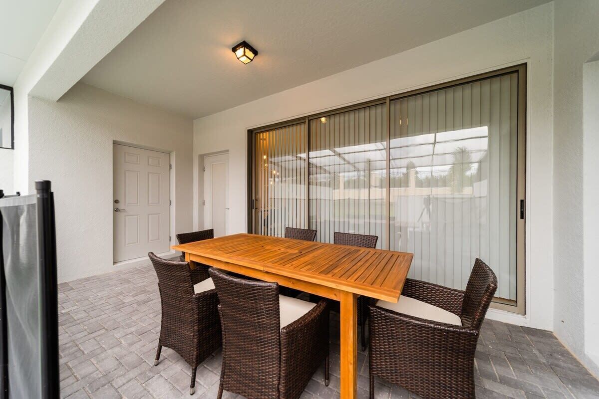 A dining area with a wooden table and wicker chairs, a sliding glass door, and a white door.
