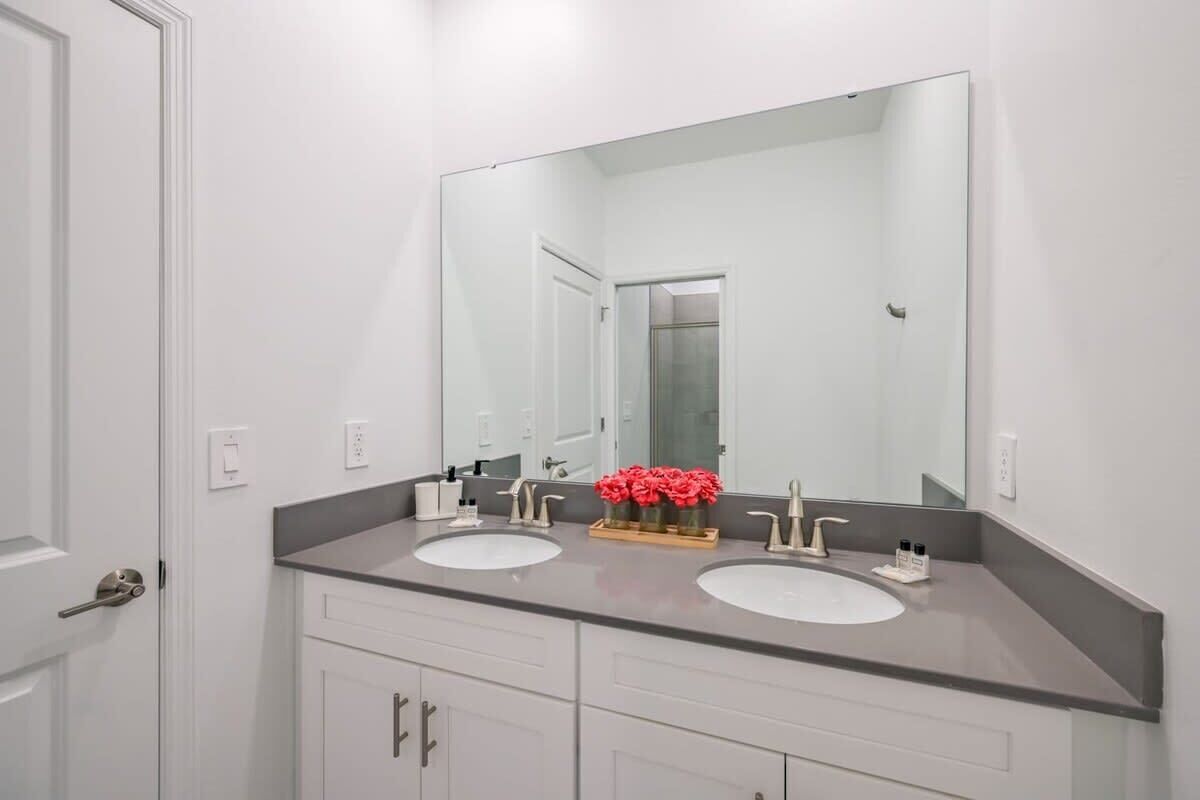 A bathroom with two sinks, a large mirror, and a door.
