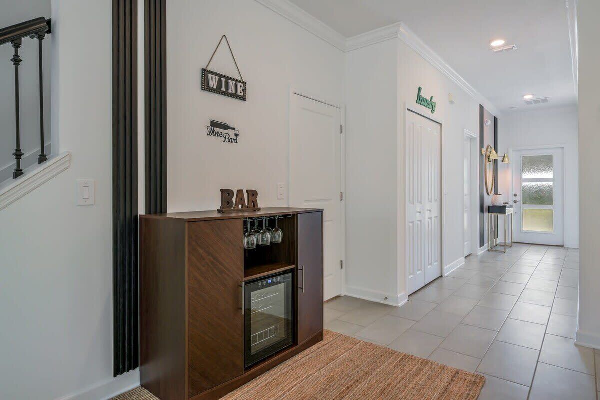 A hallway with a wooden cabinet, wine and bar signs, and a door labeled 'Lounge'.
