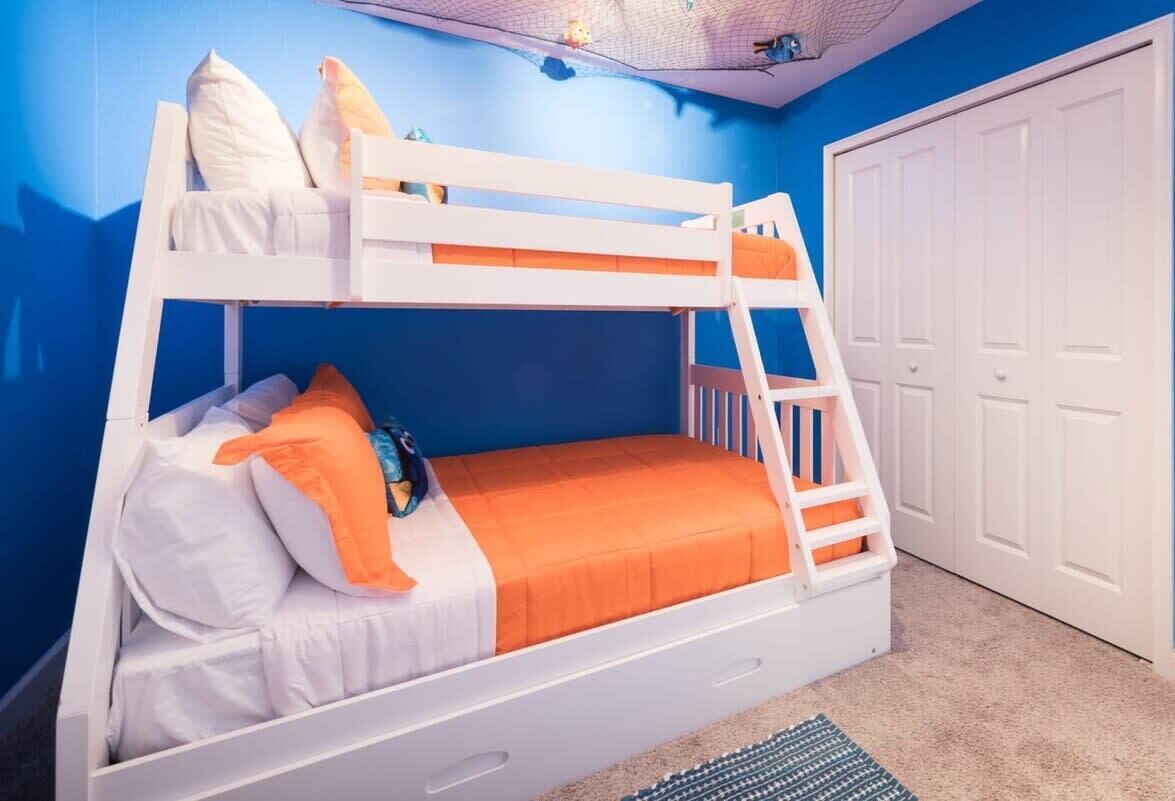 A bunk bed with white and orange bedding, a ladder, and a white door in the background.