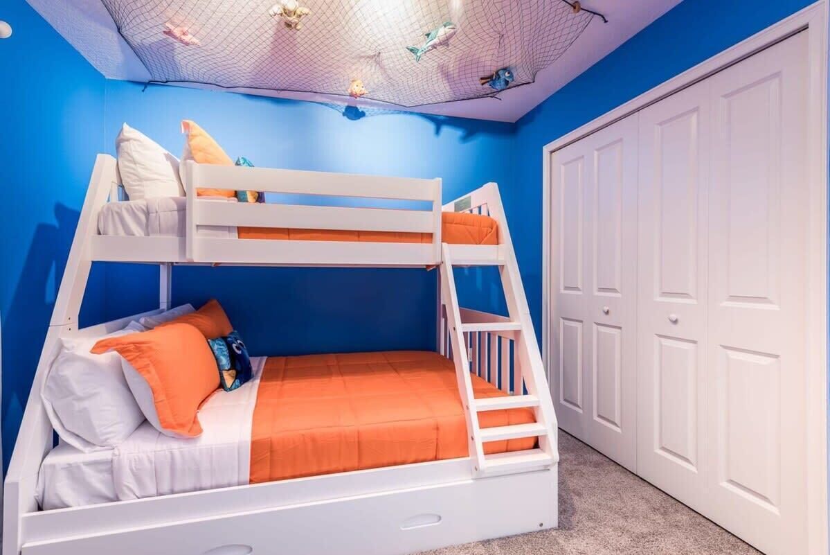 Een slaapkamer met stapelbedden, een witte ladder, een witte deur en een blauwe muur.