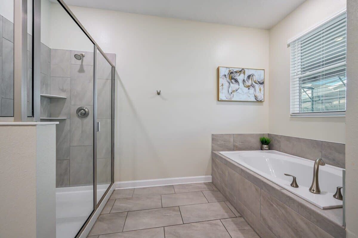 Ein modernes Badezimmer mit einer Glasdusche, einer großzügigen Badewanne und einem an der Wand befestigten Kunstwerk.