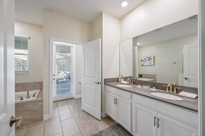 Een moderne badkamer met twee wastafels, een grote spiegel en een deur naar een balkon.