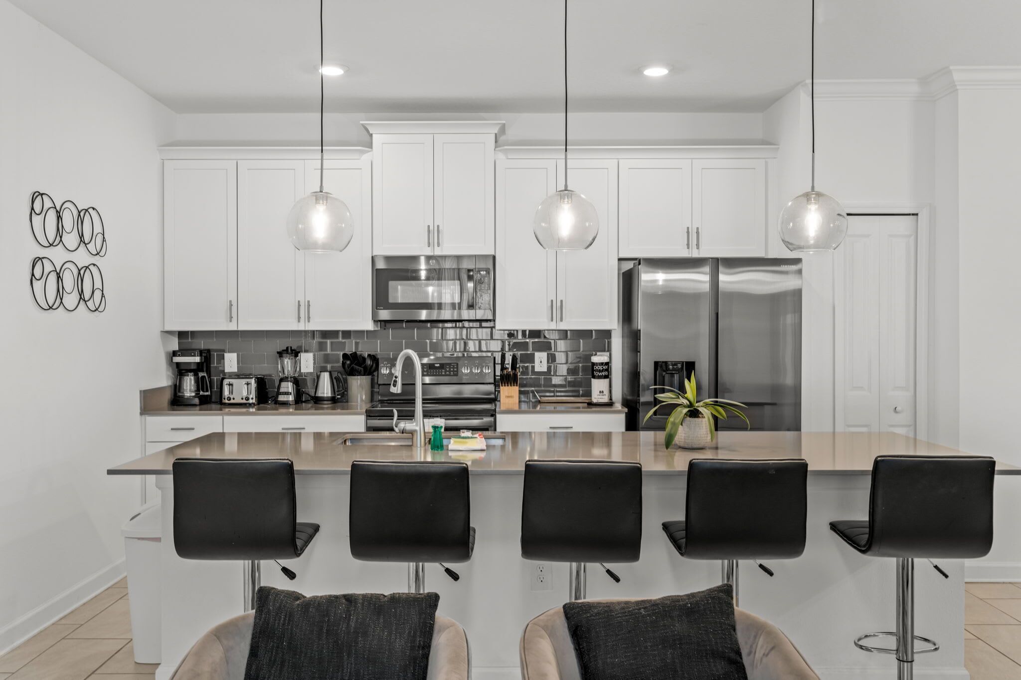A modern kitchen with white cabinets, stainless steel appliances, and a central island with bar stools.