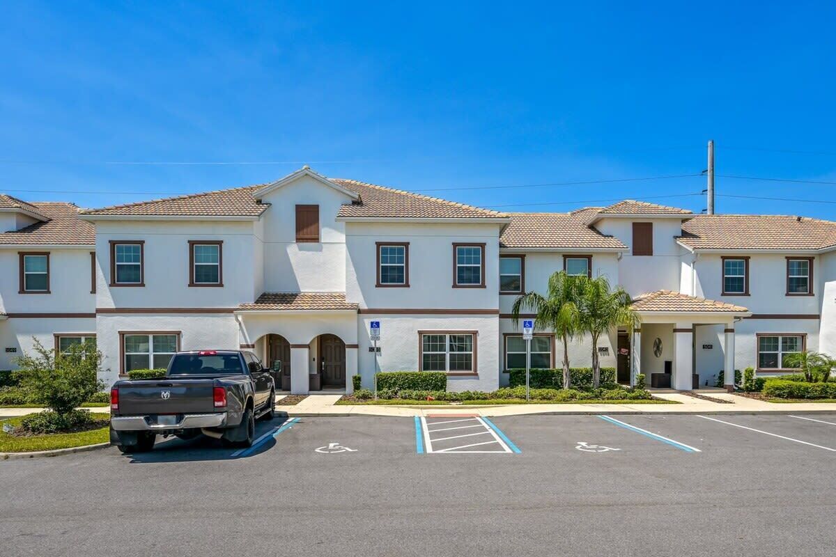 A multi-story hotel with a parking lot, a pickup truck, and a covered entrance.