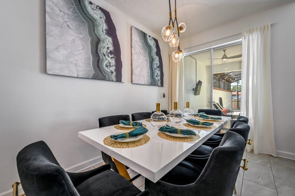 A dining area with a white table, black chairs, and abstract wall art.