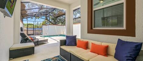 A covered outdoor seating area with a sofa, chairs, and a small table.
