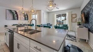 Une cuisine moderne dotée d’un îlot central, de luminaires suspendus et d’un coin repas avec un canapé et des chaises.