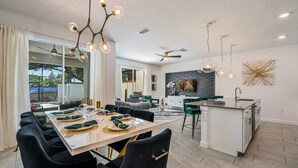 Une cuisine moderne dotée d’un îlot central, d’un coin repas avec des chaises noires et d’un ventilateur de plafond.