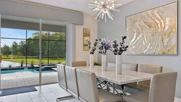 A dining area with a large table, chairs, and a view of a swimming pool.