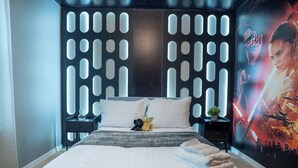 Una habitación de hotel con una cama, una mesita de noche, una pared con diseño de estrellas y un cartel en la pared.