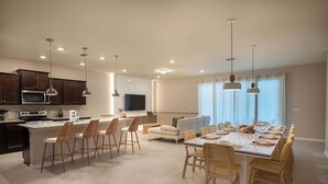 Una cocina moderna con una isla central, taburetes de bar e iluminación colgante.