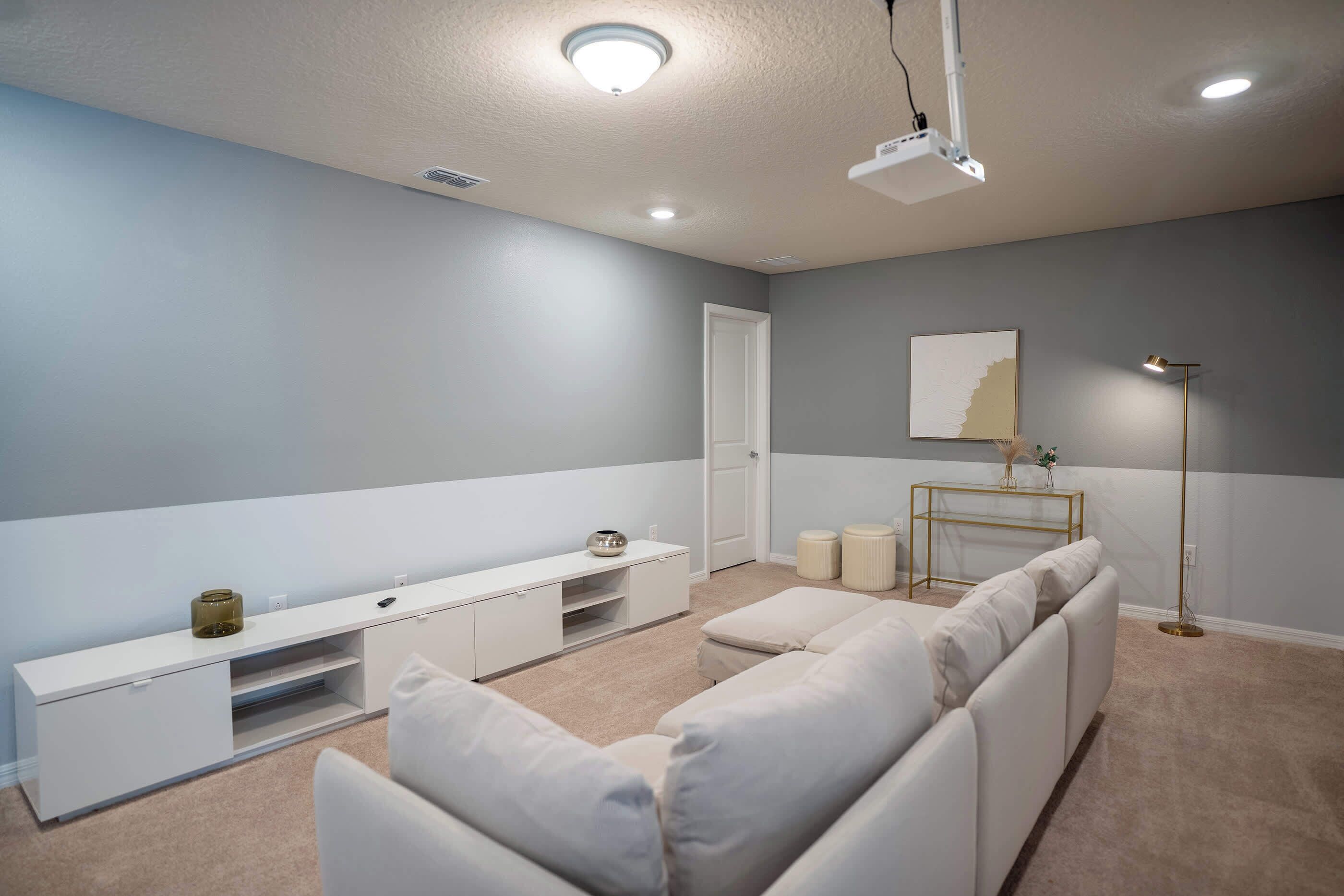 Una habitación moderna con un sofá blanco, una mesita consola blanca, una lámpara de pie y un cuadro en la pared.