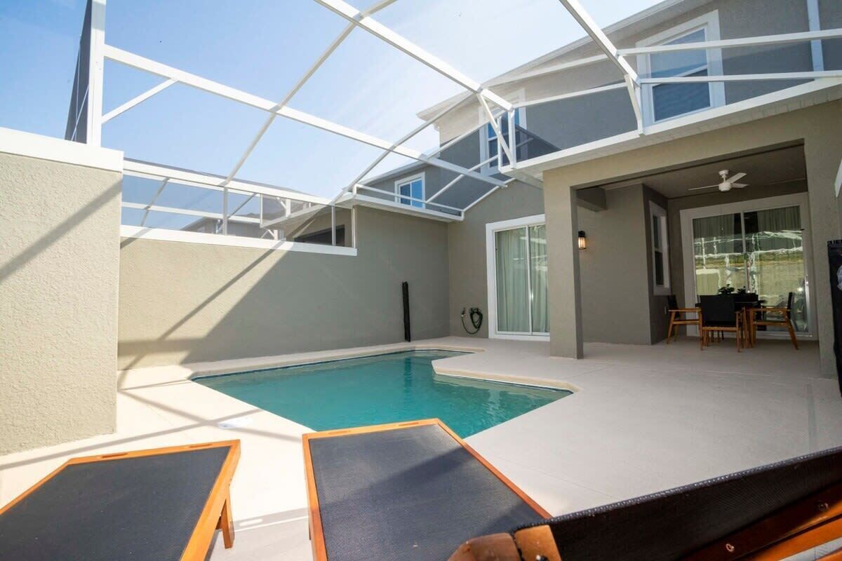 Ein moderner Poolbereich im Innenbereich mit Glasdächern, Liegestühlen und einem Essbereich.